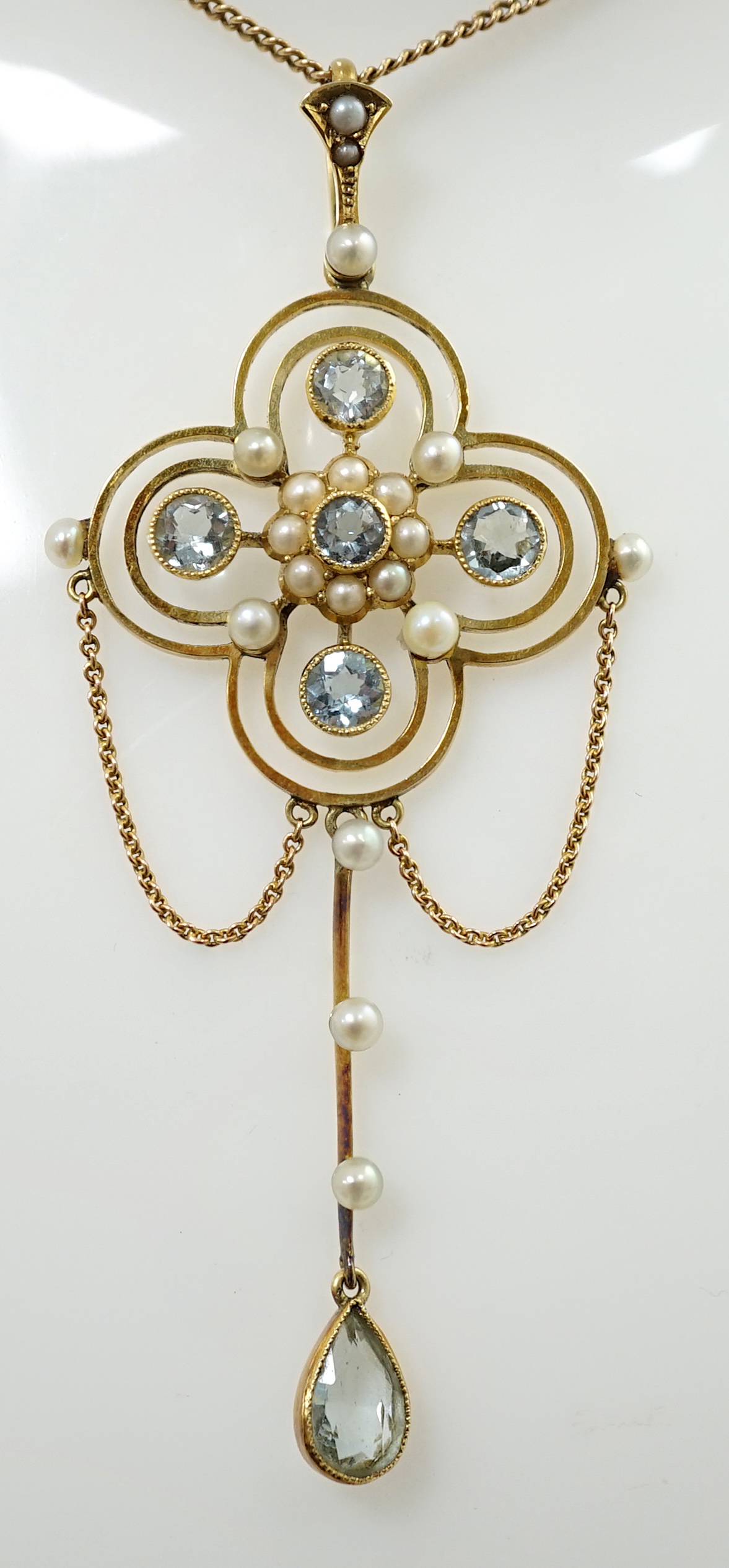 An Edwardian 15ct gold, aquamarine and seed pearl cluster set drop pendant, on a 15ct gold fine link chain